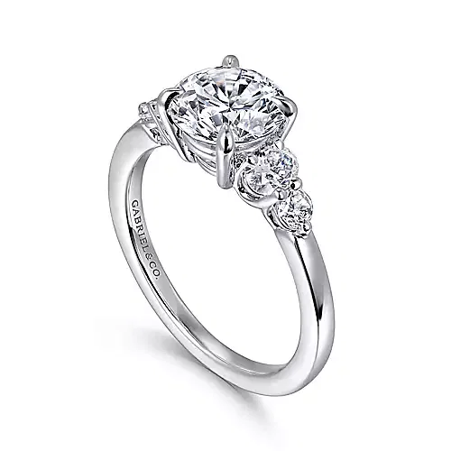 white gold engagement ring with one round and one oval diamond on either side of center stone