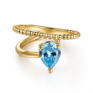 pear shape blue topaz prong set with bujukan details, asymmetrical design in yellow gold