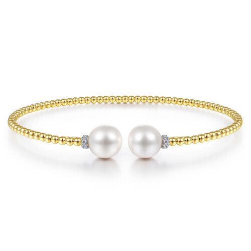 yellow gold beaded bangle with small diamond details and a pearl on each end